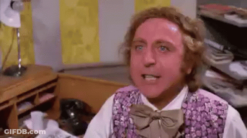 A Man Wearing A Purple Vest And Bow Tie Is Sitting At A Desk In An Office . GIF