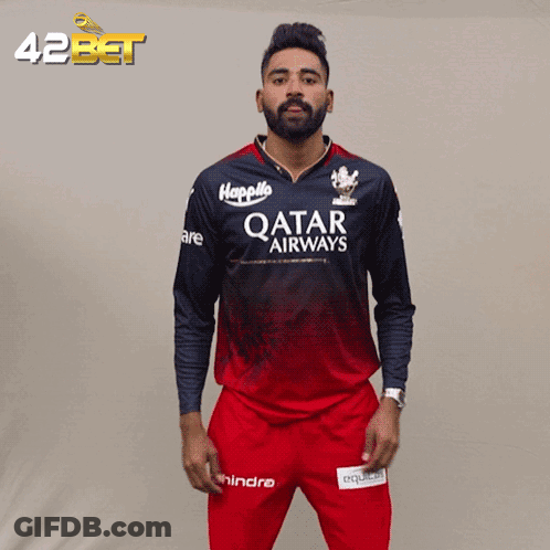 A Man Wearing A Qatar Airways Jersey Stands In Front Of A 42Bet Banner GIF