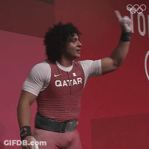 A Man Wearing A Qatar Shirt Holds His Fist Up GIF