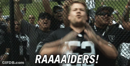 A Man Wearing A Raiders Jersey Stands In Front Of A Crowd GIF