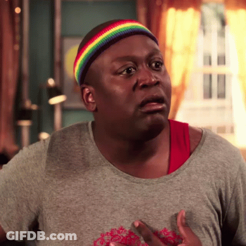 A Man Wearing A Rainbow Headband And A Gray Shirt Is Making A Funny Face GIF