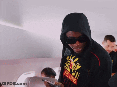 A Man Wearing A Rc Lens Shirt Looks At His Cell Phone GIF