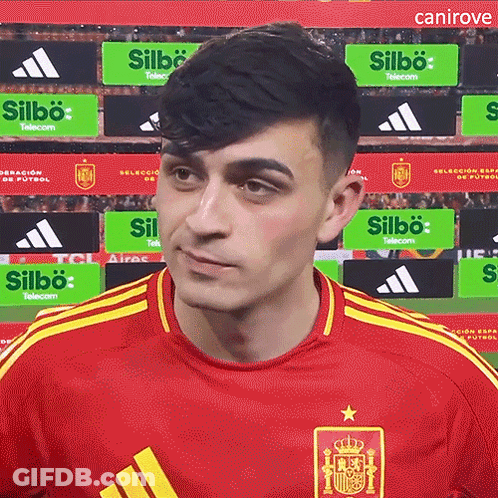 A Man Wearing A Red Adidas Shirt Stands In Front Of A Sign That Says Silbo Telecom GIF