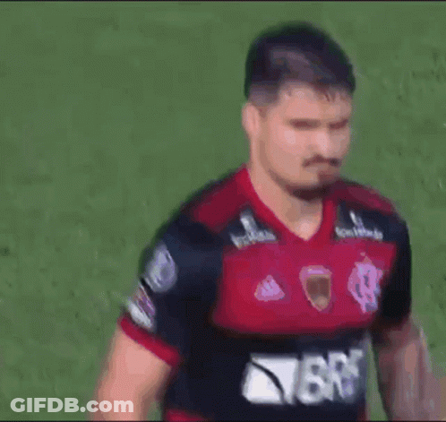 A Man Wearing A Red And Black Jersey With The Word Brb On It Is Standing On A Field . GIF