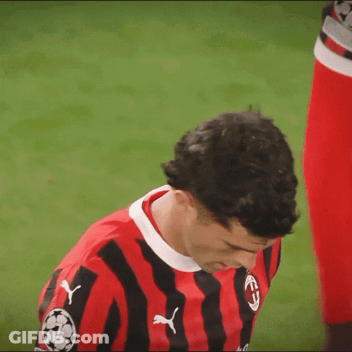 A Man Wearing A Red And Black Striped Shirt With Pumas On The Front GIF