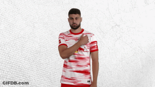 A Man Wearing A Red And White Jersey With A Red Bull On The Front GIF