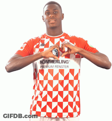 A Man Wearing A Red And White Shirt That Says Kommerling Premium Fenster Makes A Heart With His Hands GIF