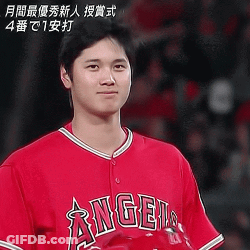A Man Wearing A Red Angels Jersey Stands In Front Of A Crowd GIF