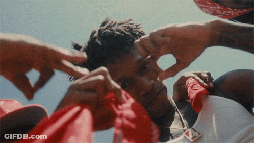 A Man Wearing A Red Bandana Is Being Touched By Other People GIF