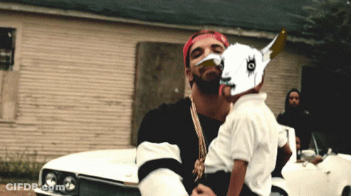 Man In Red Bandana Holding Child In Front Of Car GIF