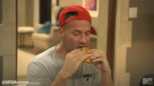 A Man Wearing A Red Baseball Cap Is Eating A Hamburger . GIF