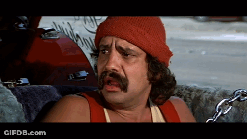 A Man Wearing A Red Beanie And A Red Tank Top With Chains Around His Neck GIF