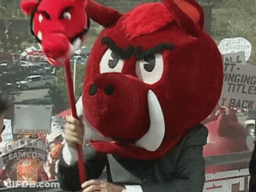 A Man Wearing A Red Boar Mascot Costume Holds A Red Stick In Front Of An Espn Sign GIF