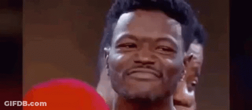A Man Wearing A Red Boxing Glove Is Smiling . GIF