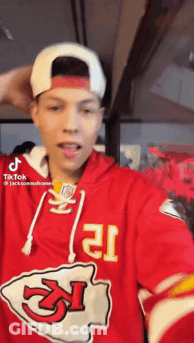 A Man Wearing A Red Chiefs Jersey And A White Hat Is Taking A Selfie . GIF