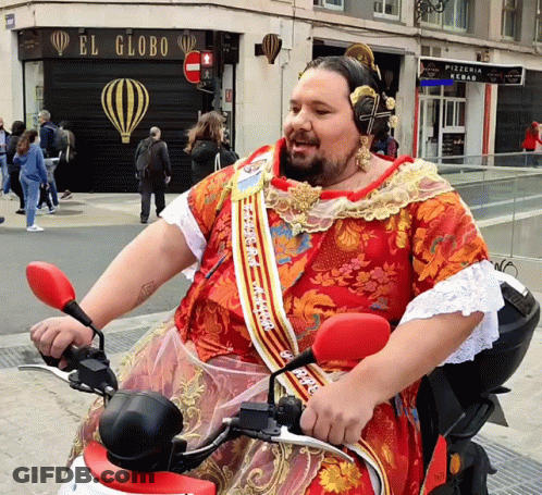 A Man Wearing A Red Dress Is Riding A Motorcycle In Front Of A Store Called El Globo GIF