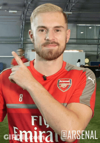 A Man Wearing A Red Fly Emirates Soccer Jersey Is Pointing Up GIF
