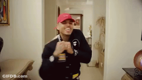 A Man Wearing A Red Hat And A Black Jacket Is Standing In A Hallway . GIF