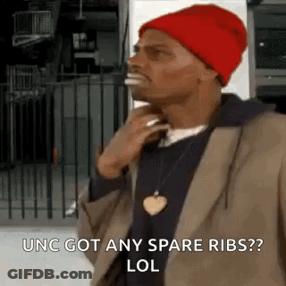 A Man Wearing A Red Hat And A Brown Jacket Is Standing In Front Of A Fence And Talking On A Cell Phone . GIF