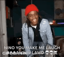 A Man Wearing A Red Hat And A Denim Jacket Is Laughing In A Dark Room . GIF
