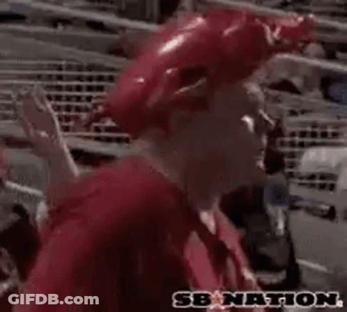 A Man Wearing A Red Hat And A Red Shirt Is Sitting In A Stadium And Saying Woo Pig . GIF