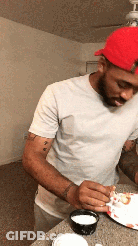 A Man Wearing A Red Hat And A White Shirt Has A Tattoo On His Arm That Says ' T.e. ' GIF