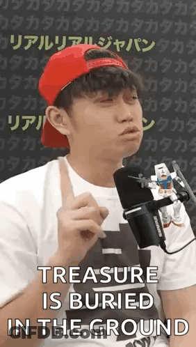 A Man Wearing A Red Hat And A White Shirt Is Talking Into A Microphone While Holding A Toy Robot . GIF