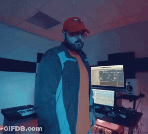 A Man Wearing A Red Hat And Sunglasses Is Standing In Front Of A Computer Monitor GIF