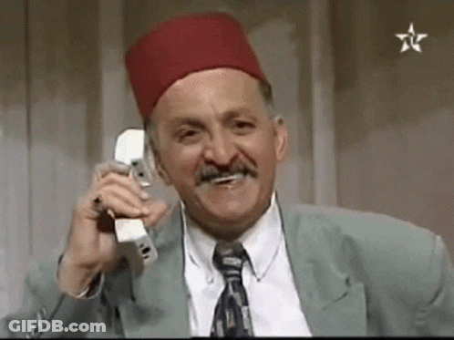 A Man Wearing A Red Hat And Tie Is Talking On A Cell Phone . GIF