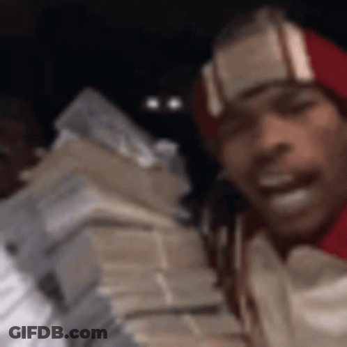 A Man Wearing A Red Hat Is Holding A Stack Of Money . GIF