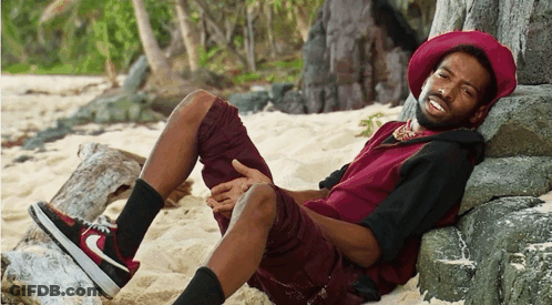 A Man Wearing A Red Hat Is Laying On A Rock GIF
