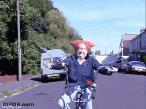 A Man Wearing A Red Hat Is Riding A Bike On A Street GIF