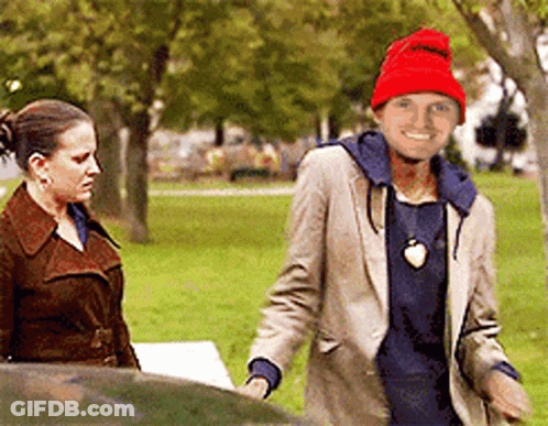 A Man Wearing A Red Hat Is Smiling While Standing Next To A Woman GIF