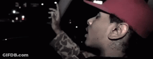 A Man Wearing A Red Hat Is Sticking Out His Tongue . GIF