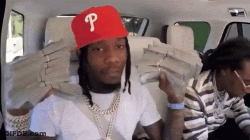 A Man Wearing A Red Hat With The Letter P On It Is Holding Stacks Of Money On His Shoulders . GIF