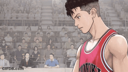 A Man Wearing A Red Hawks Jersey Stands In Front Of A Crowd Of People GIF