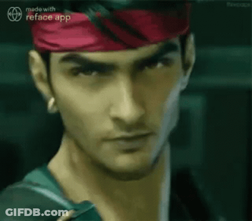 A Man Wearing A Red Headband And A Green Shirt Is Looking At The Camera . GIF
