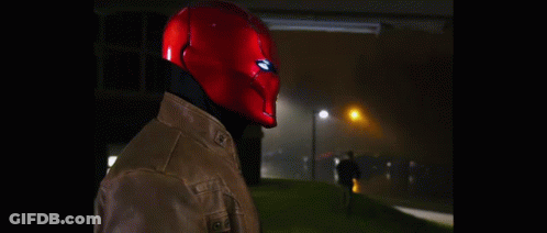 A Man Wearing A Red Helmet And A Leather Jacket Is Standing In The Dark . GIF
