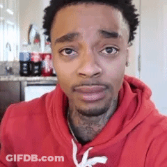 A Man Wearing A Red Hoodie Is Looking At The Camera . GIF