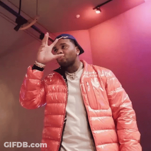 A Man Wearing A Red Jacket And A Blue Hat Making A Peace Sign GIF