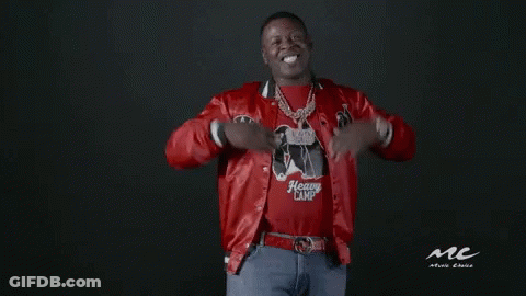 A Man Wearing A Red Jacket And A Heavy Camp Shirt Is Standing In Front Of A Black Background . GIF