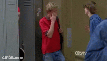 A Man Wearing A Red Jacket And A Music Band Shirt Is Carrying A Skateboard On His Shoulder . GIF