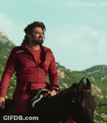 A Man Wearing A Red Jacket Is Riding A Black Horse GIF