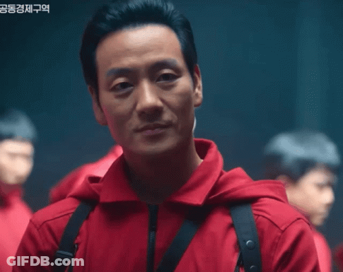 A Man Wearing A Red Jacket With A Black Strap Around His Neck GIF
