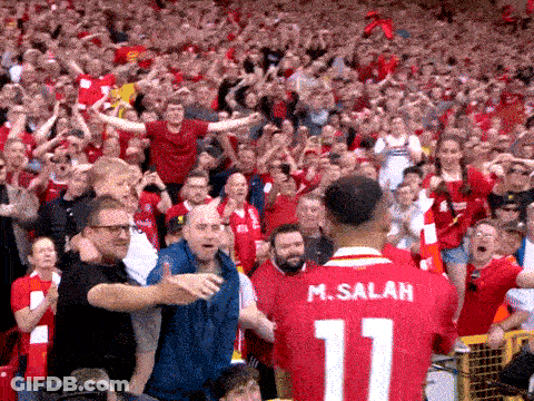 A Man Wearing A Red Jersey With The Number 11 On It Stands In Front Of A Crowd GIF