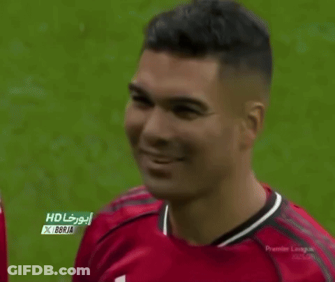 A Man Wearing A Red Manchester United Jersey Is Smiling On A Soccer Field . GIF