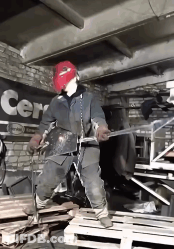 A Man Wearing A Red Mask Is Welding In Front Of A Sign That Says Cern GIF