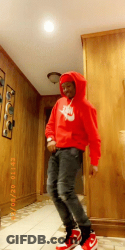 A Man Wearing A Red Nike Hoodie Is Standing In A Hallway GIF