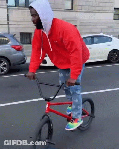 A Man Wearing A Red Nike Jacket Is Riding A Red Bike GIF