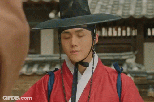 A Man Wearing A Red Robe And A Black Hat . GIF